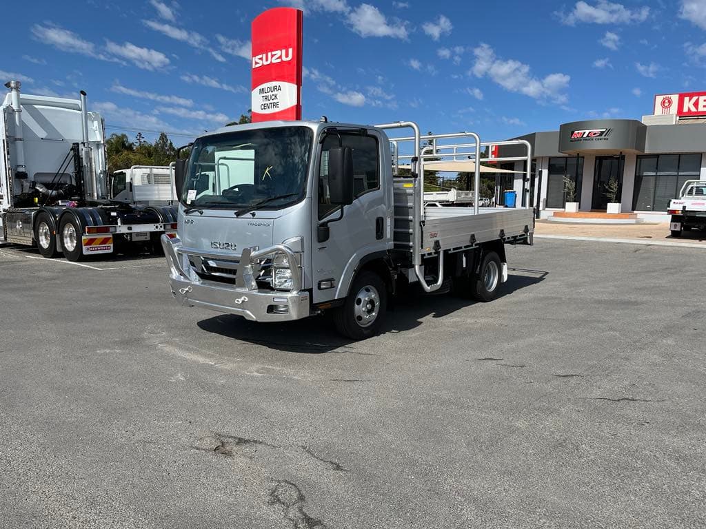 Silver Isuzu NPR cab-chassis light truck with tray body at the dealership